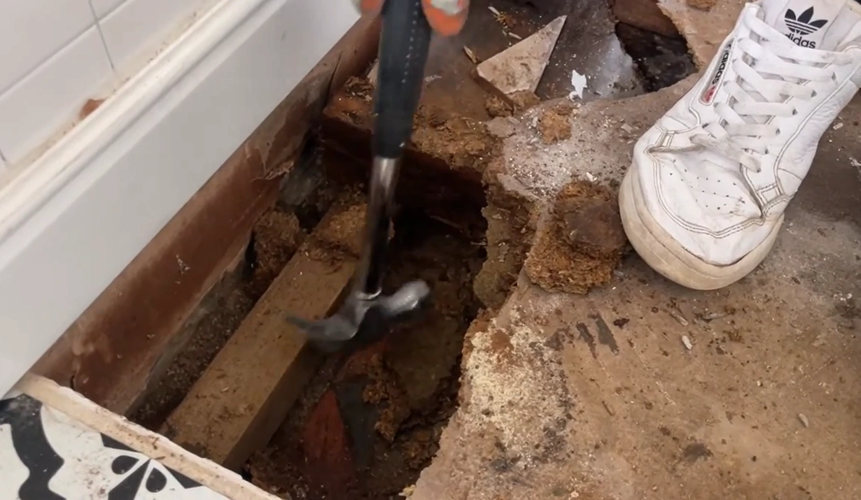 Emergency water damage response in Lincoln, NE — technician tearing out a water-damaged subfloor